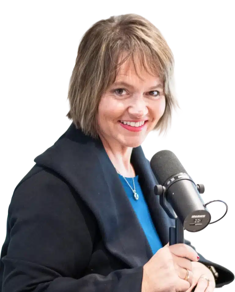 Kim Walker with short, light brown hair and a black blazer smiles while speaking into a black Shure microphone, appearing to be recording or hosting a podcast.
