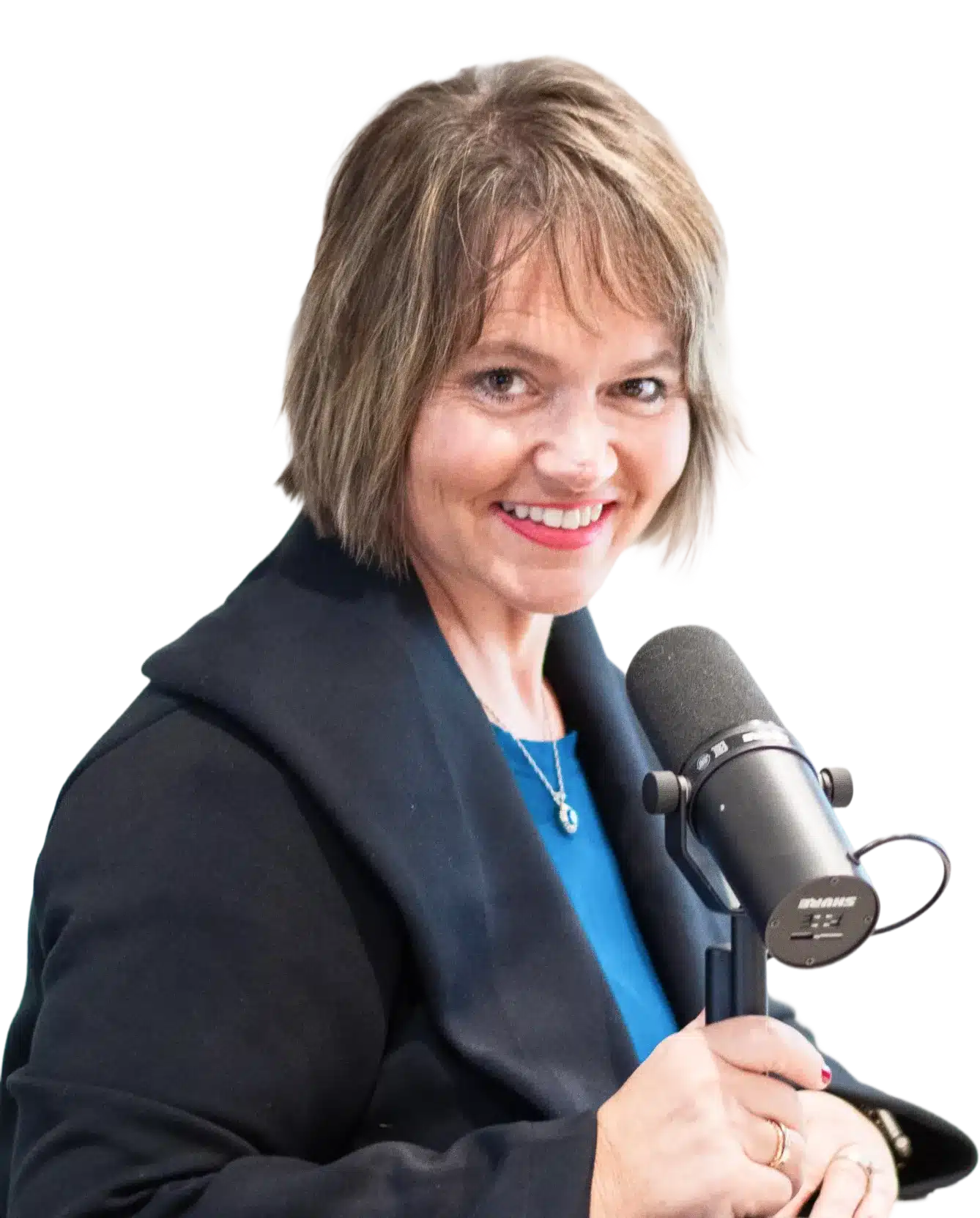 Kim Walker with short, light brown hair and a black blazer smiles while speaking into a black Shure microphone, appearing to be recording or hosting a podcast.